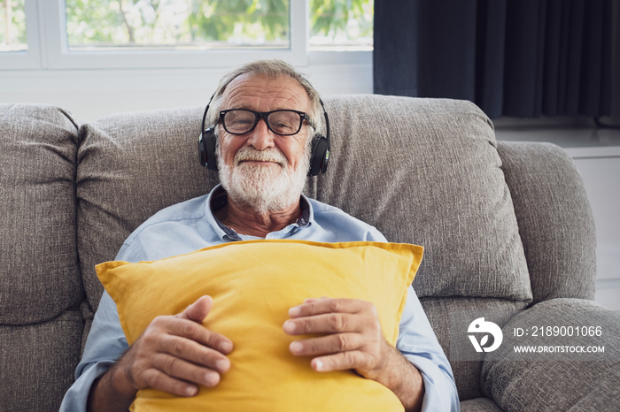 senior man happiness sitting on the sofa and listening music with headphone at living room for relax