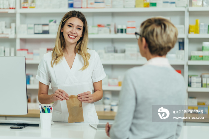 Female pharmacist selling medications at drugstore to a senior woman customer