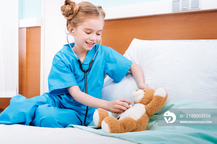 portrait of smiling girl nurse listening teddy bears heartbeat with stethoscope