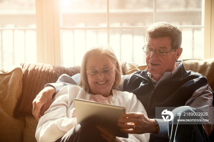 Senior couple using tablet pc in living room