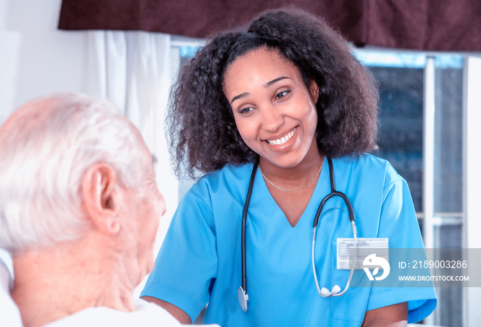 Caucasian male senior smiling with female african doctor at the hospital. Retired elderly people liv