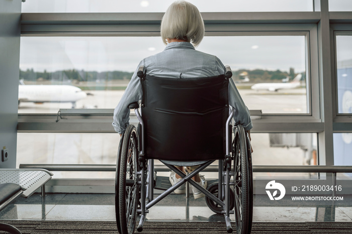 Elderly woman is using a wheelchair in lobby before flight