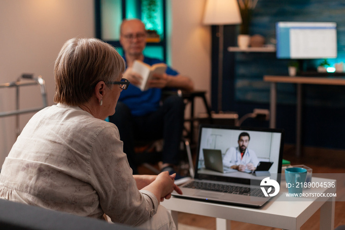 Sick older patient using telemedicine on video call conference while sitting on couch at home. Senio