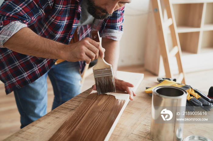 Man painting a raw board with a protective preparation