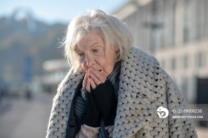 Grey-haired homeless pensioner feeling very cold outside