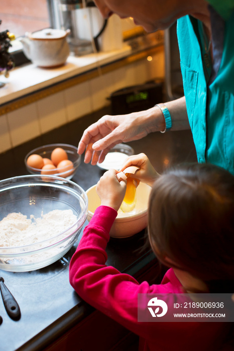 Grandmother with granddaughter (4-5) preparing cake in kitchen