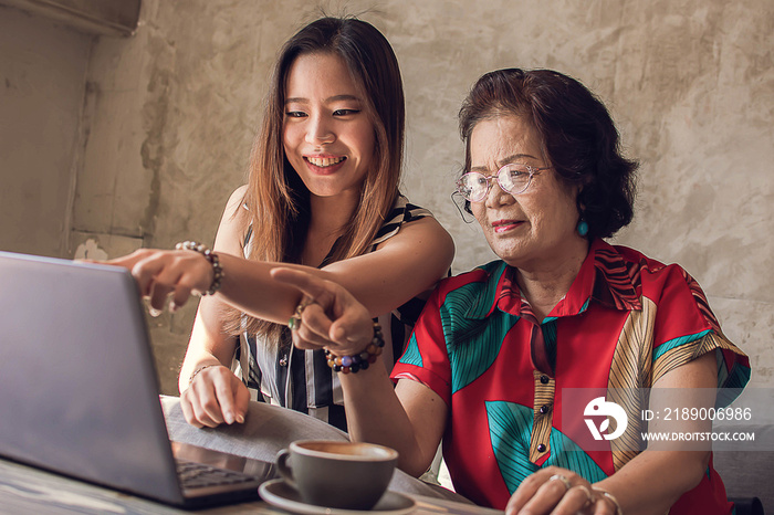 Young and old asian women are using laptop together