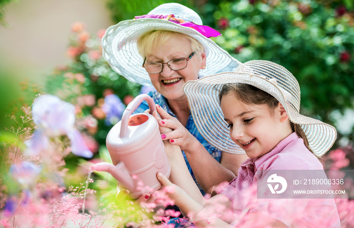 Gardening with kids. Senior woman and her grandchild working in the garden with a plants. Hobbies an