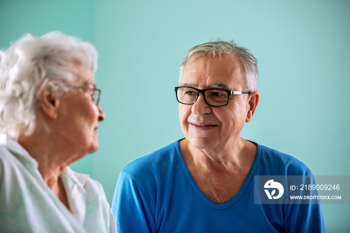 Senior man and elder woman sitting on the bed in a nursing home