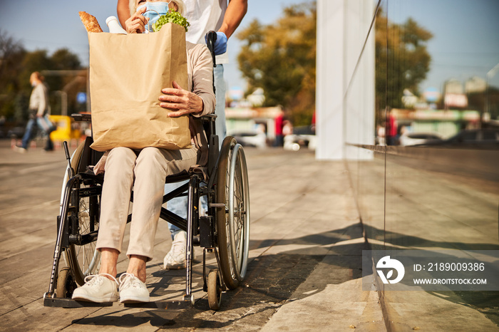 Old-aged female in a wheelchair carrying a food envelope