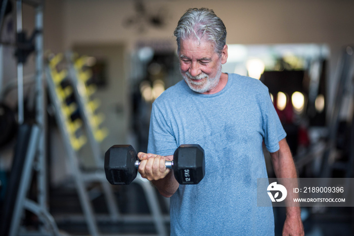 one mature man holding a weight at the gym doing exercise to be healthy and fitness - senior in a gy