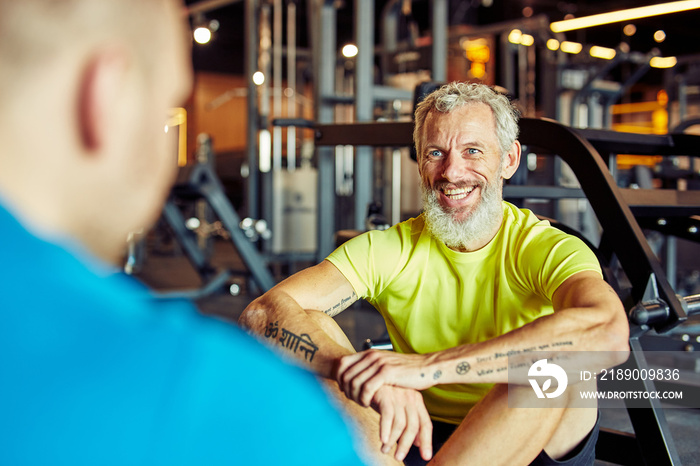 Portrait of a happy middle aged man discussing training results with fitness instructor or personal 