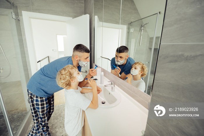 Pleasant nice man teaching his son to shave