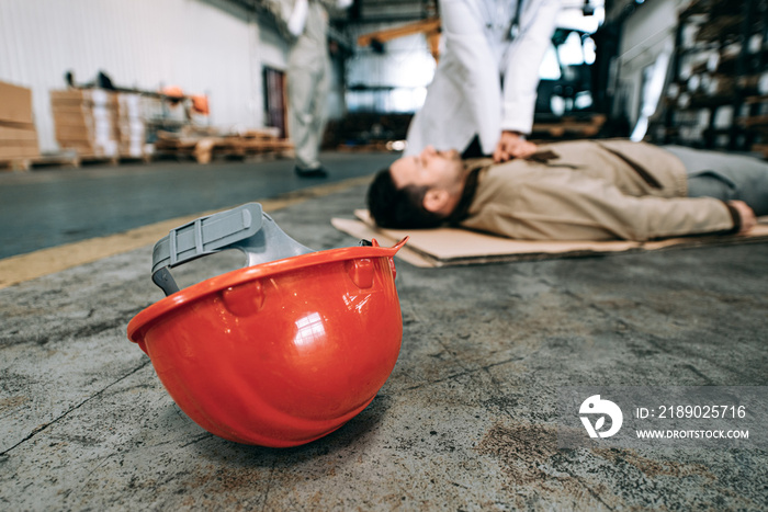 Unconscious worker lying on a warehouse floor.