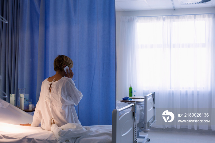 Female patient using smart phone in hospital bed