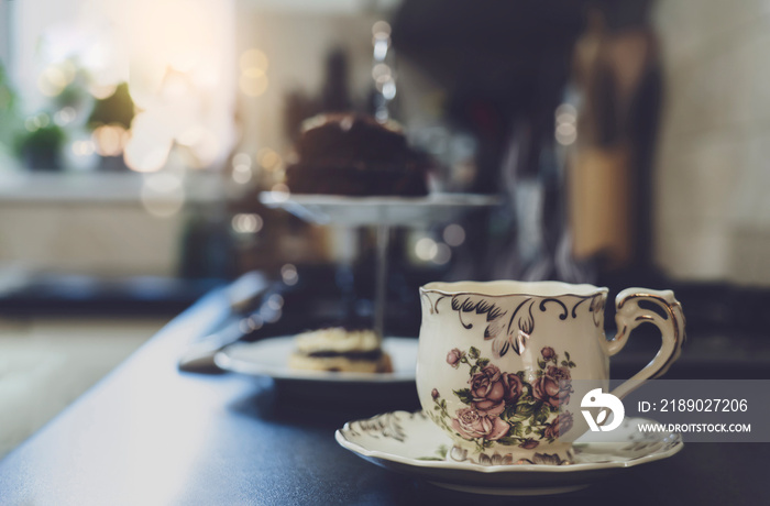 一杯热茶，厨房背景的高茶架上有模糊的蛋糕。一杯香气四溢的智慧