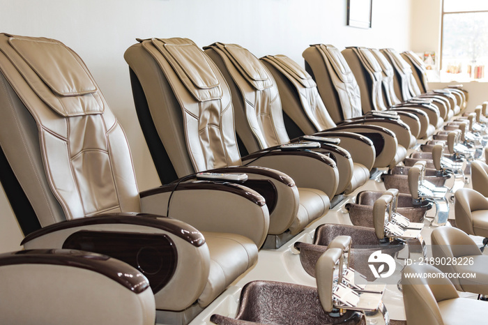 A row of pedicure chairs looking towards the front of a shop.  Background blurry.