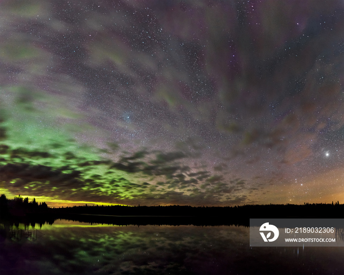 Aurora, stars and clouds reflecting in a calm lake