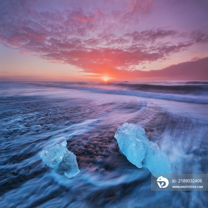 Beautiful sunset over famous Diamond beach, Iceland. This sand lava beach is full of many giant ice 