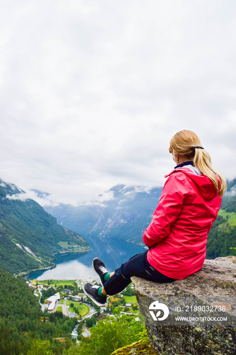 坐在Flydalsjuvet Viewpoint附近悬崖边上的女游客。挪威旅游，