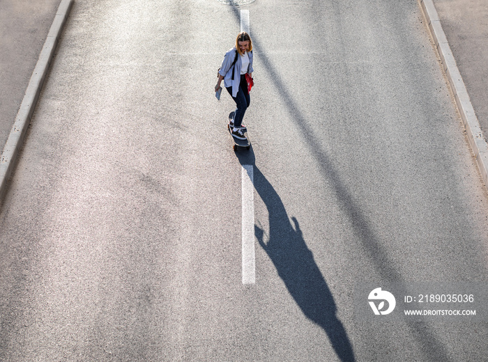 Top view of smiling girl driving long board in the city.