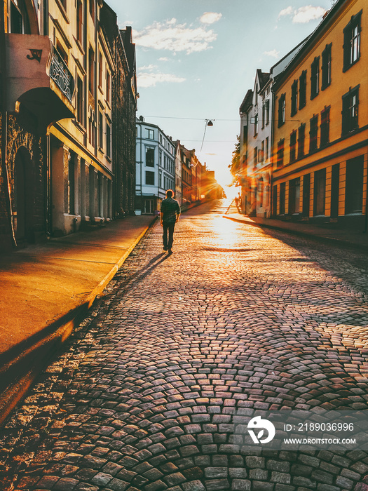 男子游客走在日落的街道上旅行生活方式概念度假鹅卵石路Alesund cit