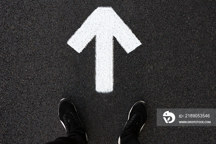 A man is standing on the road. Forward arrow