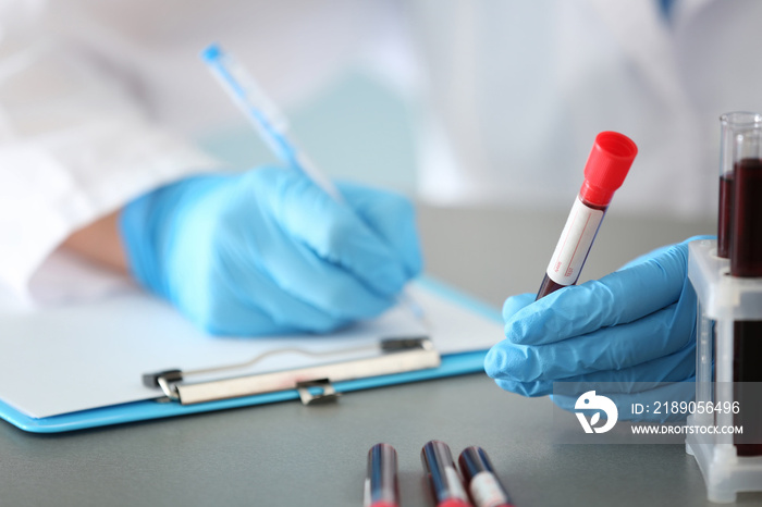 Woman working with blood sample in test tube at table