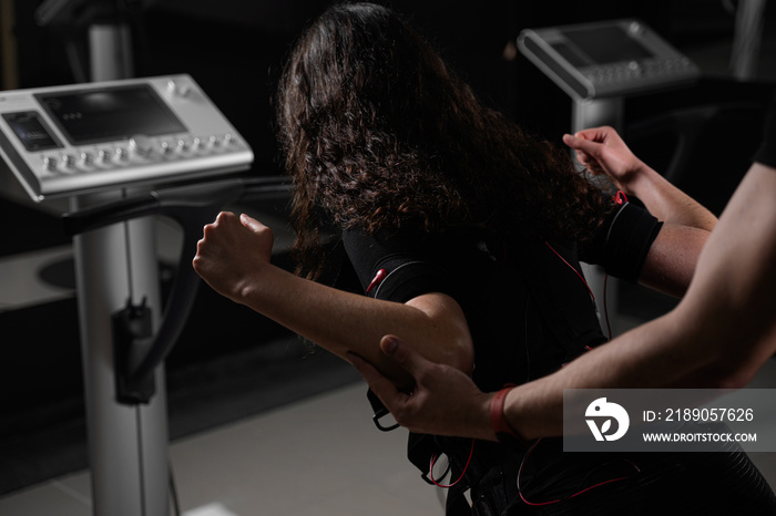 Girl in EMS suit in gym. Sport training in electrical muscle stimulation suit.