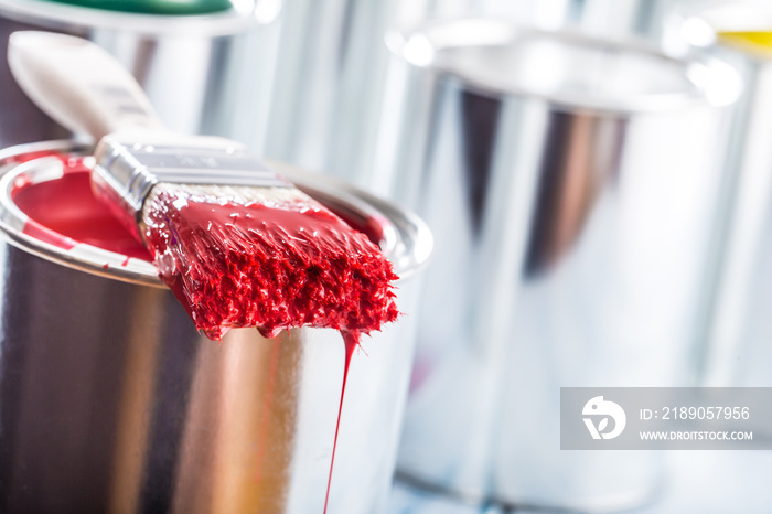 Close-up brush with red color lying on paint can.