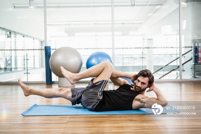 Muscular man doing abdominal on mat