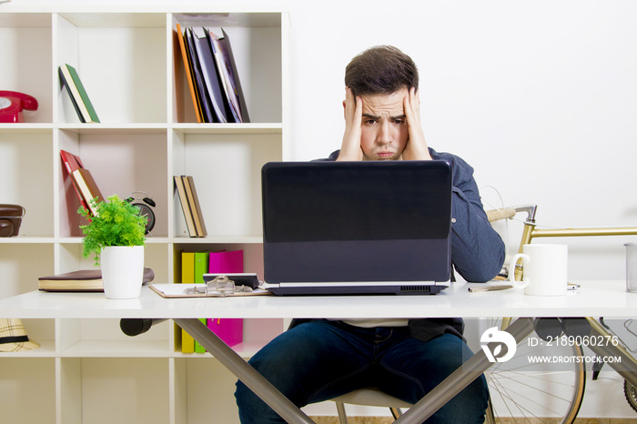 young man in front of the computer laptop concentrated or overwhelmed