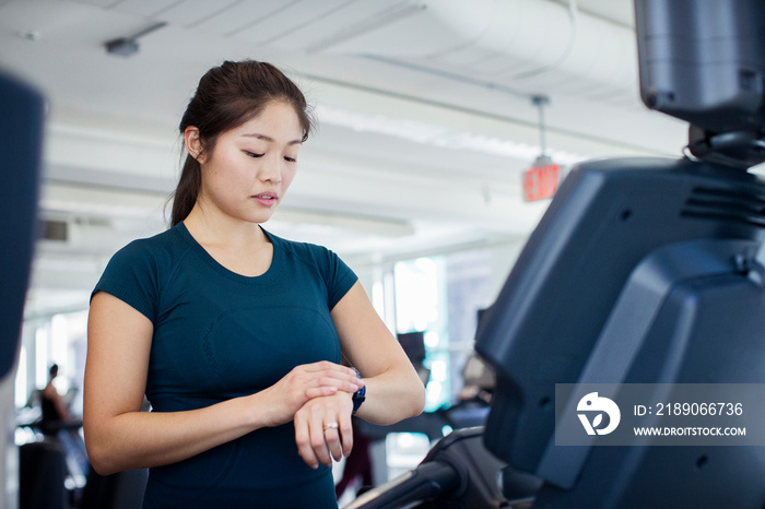 Woman checking time while exercising on treadmill in gym