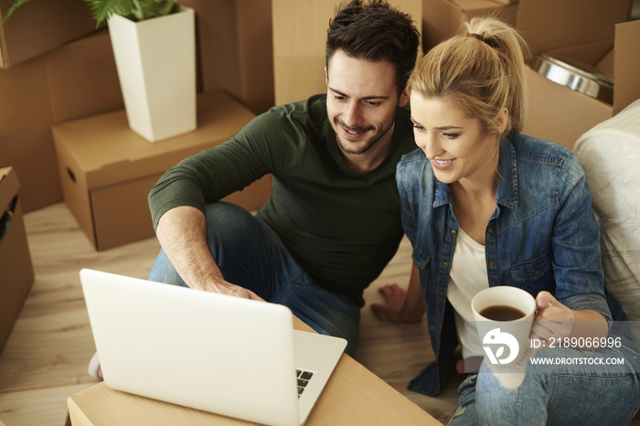 Beautiful couple using laptop among cartons