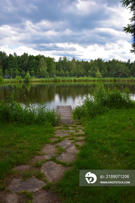 一条石头小路通向风景如画的河岸上的一个小木墩。背景图片