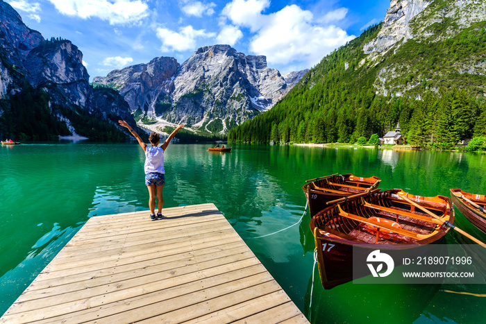 Woman relaxing on Pier at Lake Braies also known as Pragser Wildsee  in beautiful mountain scenery. 