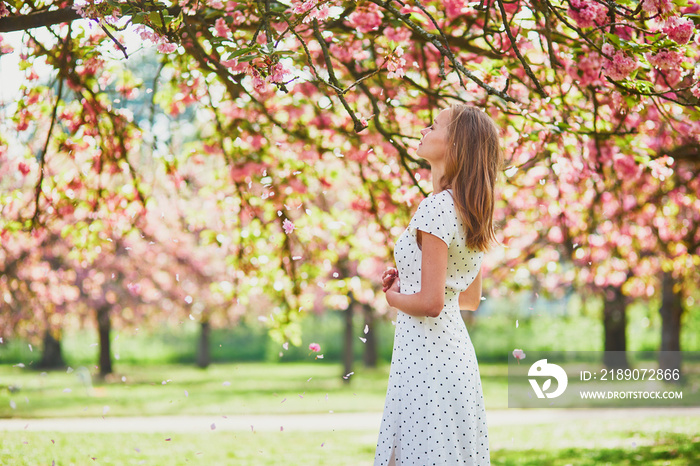在一个美好的春天，樱花盛开的季节，一位年轻的女士在公园里散步
