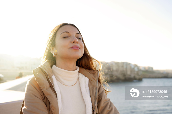 Portrait of young charming woman breathing fresh air relaxing with closed eyes on the beach