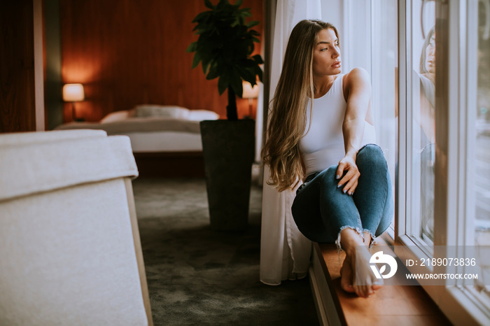 Beautiful young woman sitting by the window