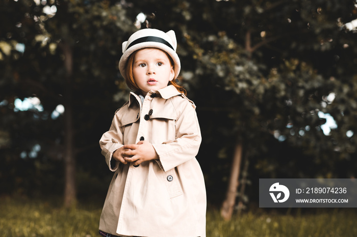 Stylish baby girl 2-3 year old wearing trendy trench outdoors closeup. Childhood.