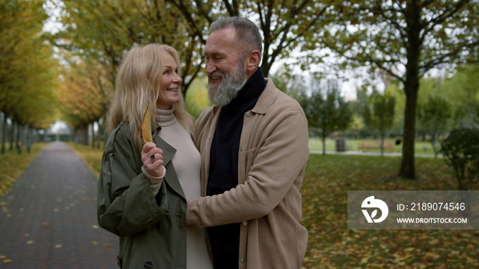 Romantic mature couple standing face to face in town park. Beautiful lovers.