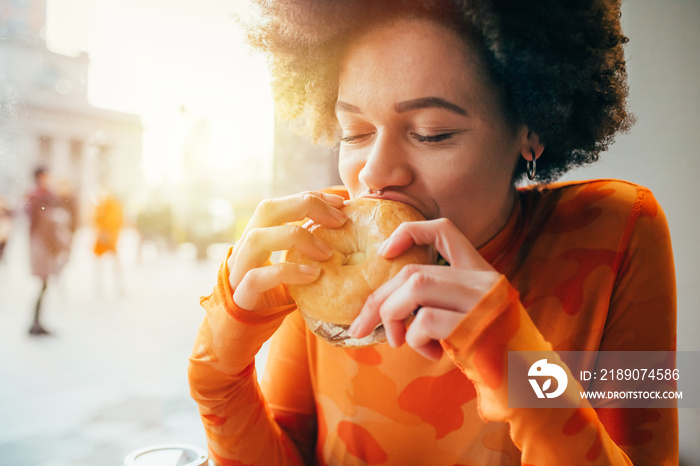 Young beautiful multiethnic woman eating hamburger