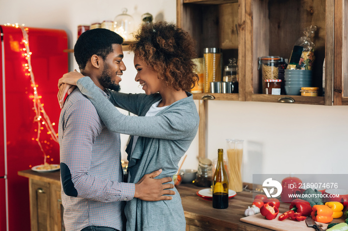 Lovely black couple embracing in cozy kitchen