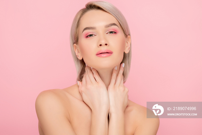 sensual naked girl with pink makeup looking at camera, isolated on pink