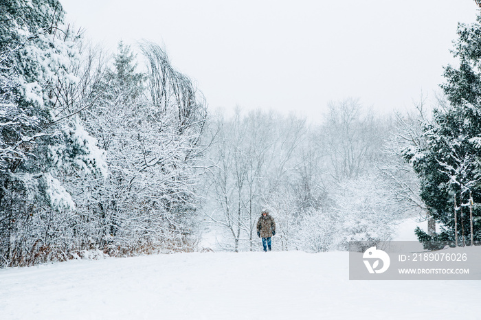 冬季户外场景。公园里的雪下行走的男人。户外有大雪和暴风雪。雪很黑