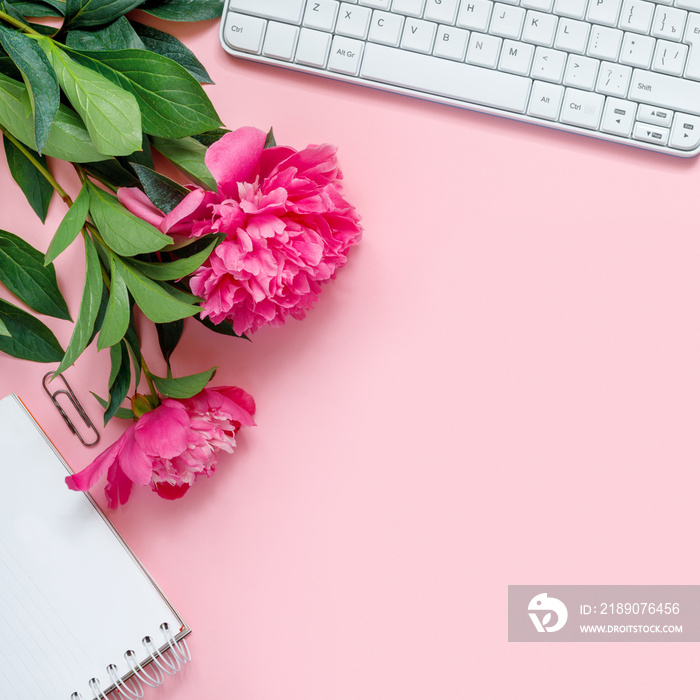 Laptop, accessories and bouquet of beautiful peonies on pink background. Flat lay of working place.