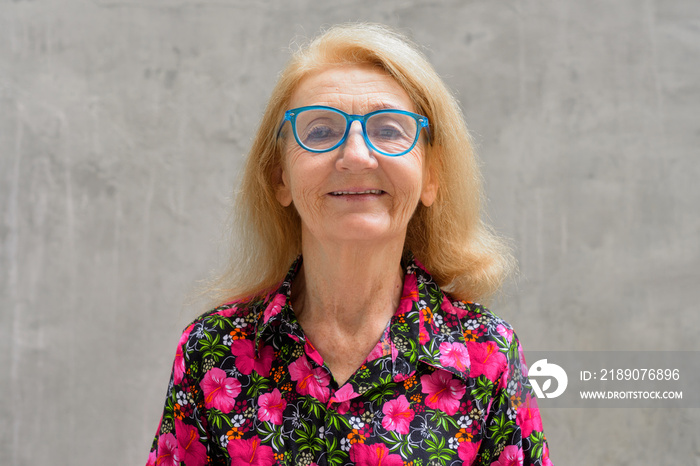 Portrait of a senior woman outdoors during summer wearing colorful shirt and eyeglasses while smilin