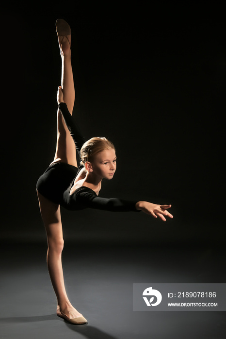 Young girl doing gymnastic exercise on dark background