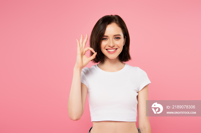 smiling pretty girl showing okay sign isolated on pink