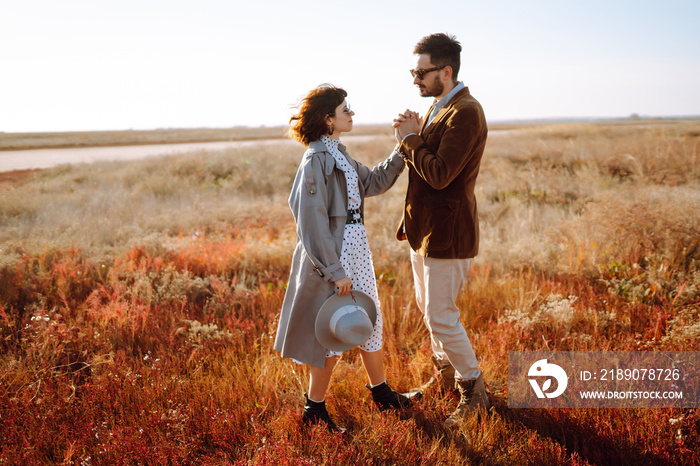 Young loving couple walking and hugging in autumn field. Enjoying time together. Fashion, lifestyle 